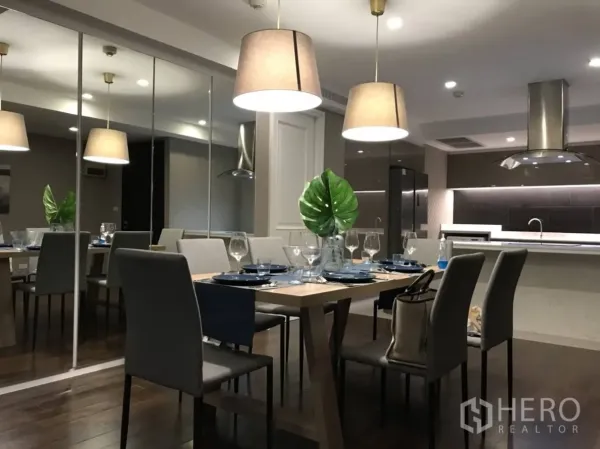 คอนโด ให้เช่าหรือขายในPathum Wan, Bangkok - พื้นที่รับประทานอาหารแบบโอเพ่นพร้อมผนังกระจก โคมไฟแขวน และมุมมองไปยังครัวโมเดิร์นในคอนโดกรุงเทพฯ