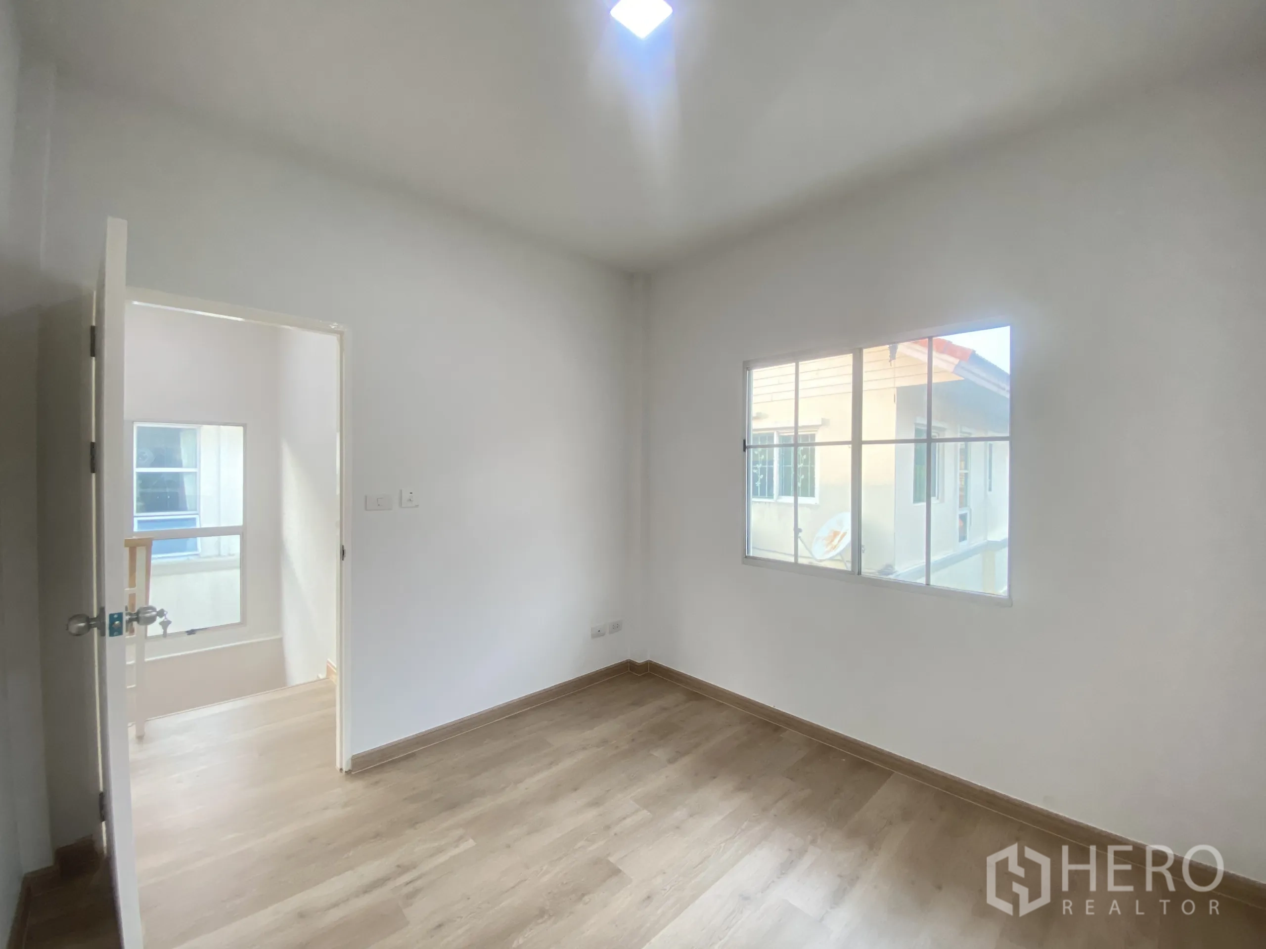 Detached House for sale in Nonthaburi - Second bedroom featuring window light and laminate wood floors.