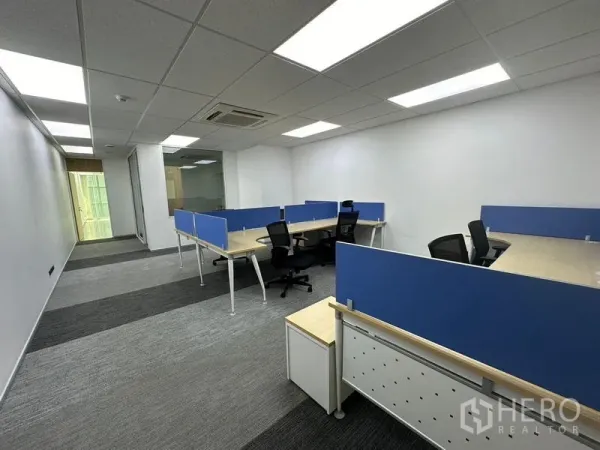 Office Space for rent - Open-plan office with blue-partition workstations, carpet tiles, and bright LED ceiling lights.