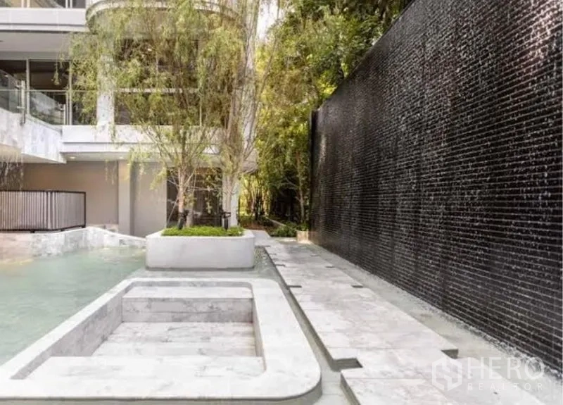 Condominium for rent in Watthana, Bangkok - Condo courtyard water feature with black tiled waterfall and trees.