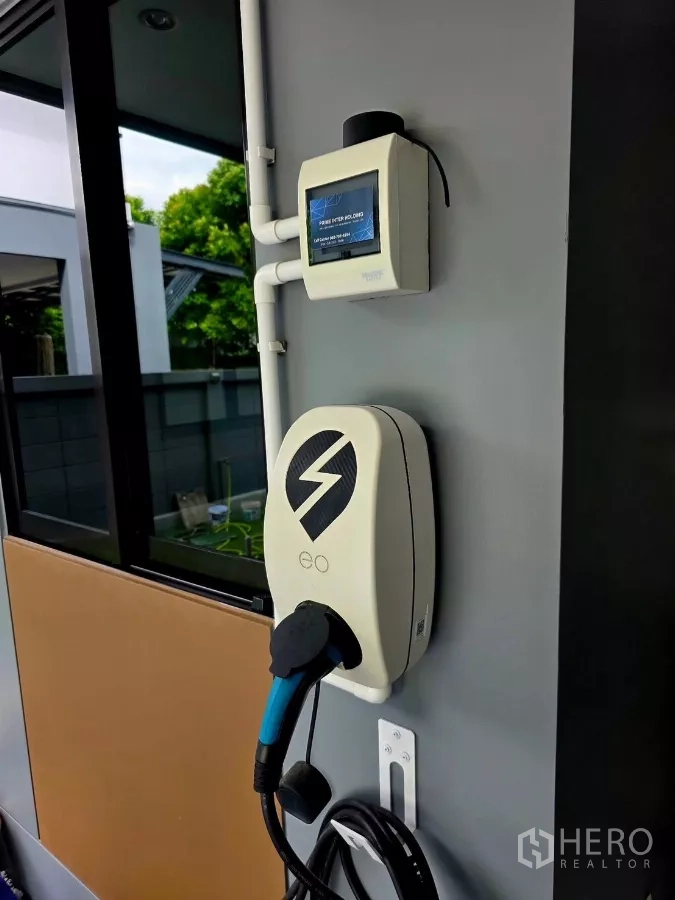 Detached House for rent in Prawet, Bangkok - EV home charger installed on the wall of the covered carport.