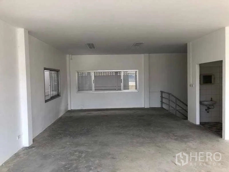 Factory for rent in Khlong Luang, Pathum Thani - Open-plan second-floor office space with windowed partition, sink, and stair access.