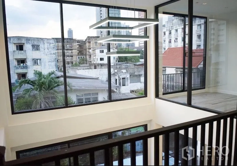 带办公室的家 出租或出售在Watthana, Bangkok - 夹层视角：巨幅窗、现代吊灯与周边城市景致。