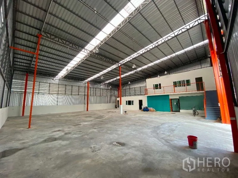 Warehouse for rent in Don Mueang, Bangkok - Open warehouse floor featuring a mezzanine office, orange support columns, and a large roller door.