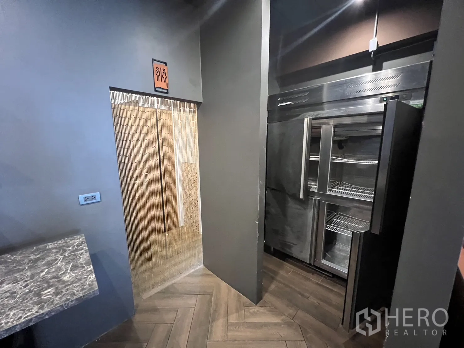 พื้นที่ขายปลีก ให้เช่าในWatthana, Bangkok - ทางเข้าห้องน้ำ ประตูไม้ไผ่เทียม ข้างตู้แช่สแตนเลส