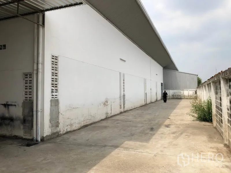 工厂 出租在Nonthaburi - 工厂侧边宽阔的混凝土空地，沿围墙延伸。