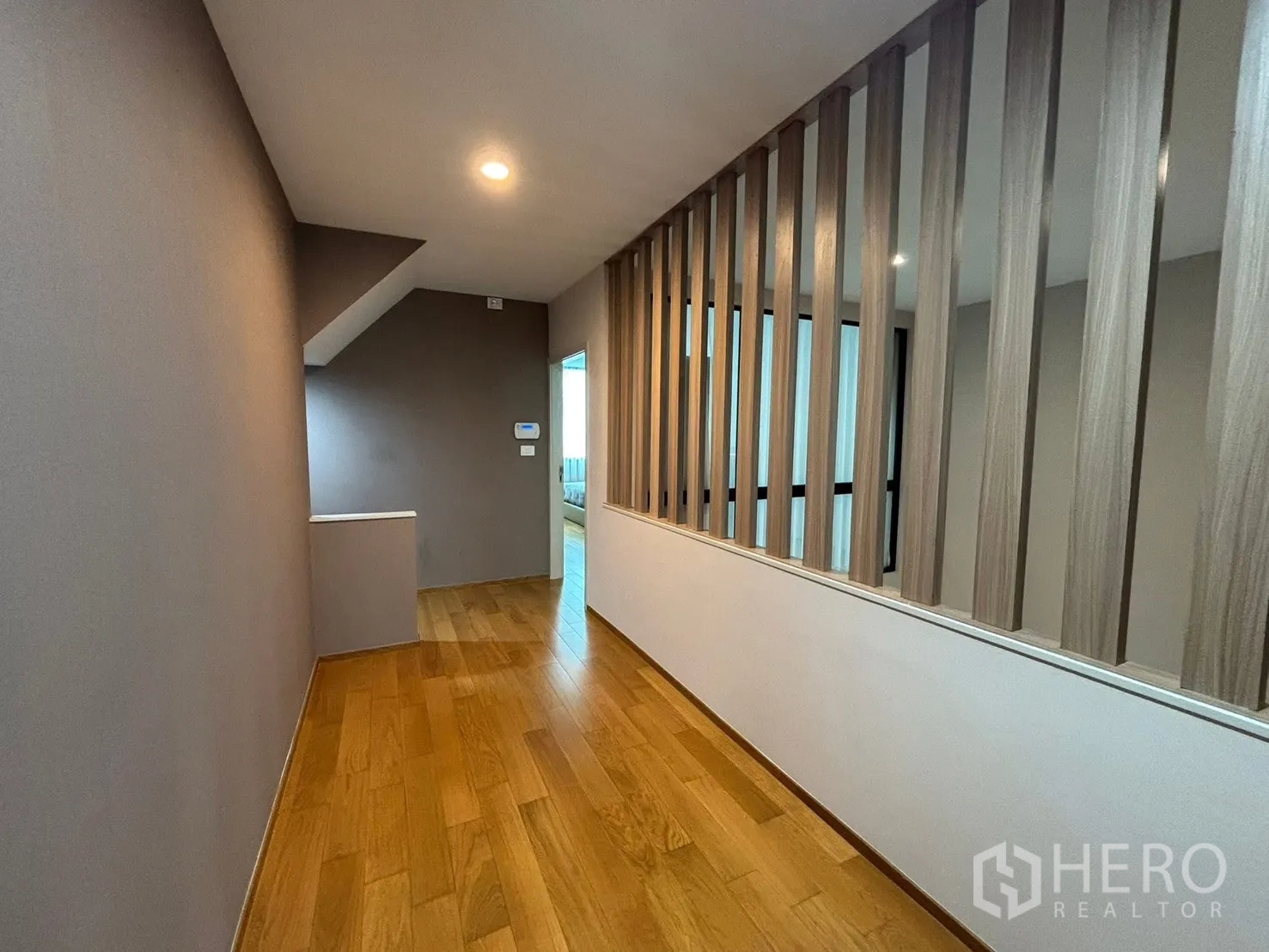 Townhouse for rent in Saphan Sung, Bangkok - Upper-floor corridor with a wood slat partition and recessed lighting.