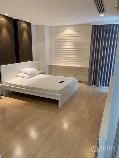 คอนโด ให้เช่าในPathum Wan, Bangkok - ห้องนอนกว้างพร้อมเตียงแพลตฟอร์ม ผนังตกแต่งไม้ ไฟดาวน์ไลท์ และผ้าม่านยาว