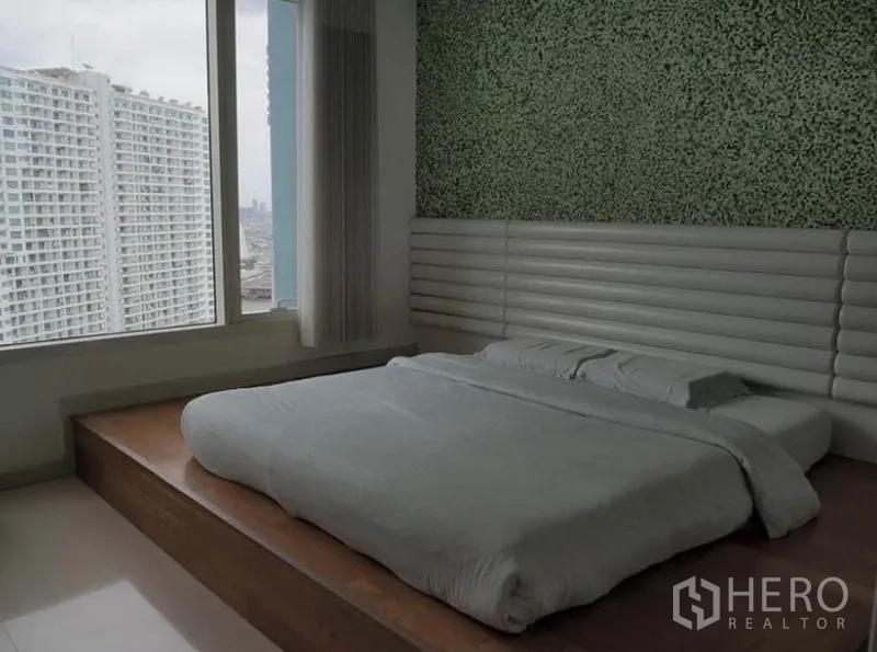 คอนโด ให้เช่าในKhlong San, Bangkok - ห้องนอนเตียงยกพื้น หน้าต่างบานใหญ่ ผนังตกแต่งสีเขียว มองเห็นวิวตึกสูง