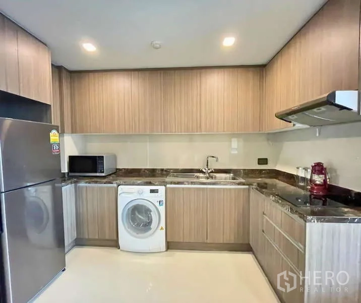 คอนโด ให้เช่า - ครัวรูปตัวแอลบิวท์อิน ตู้ลายไม้ เคาน์เตอร์หิน เครื่องซักผ้า ตู้เย็น ไมโครเวฟ และเตาพร้อมฮูด