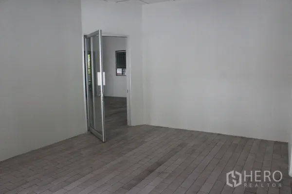Home Office for rent in Khlong Toei, Bangkok - Clean tiled lobby or office room with white walls and an open glass door leading to another room.