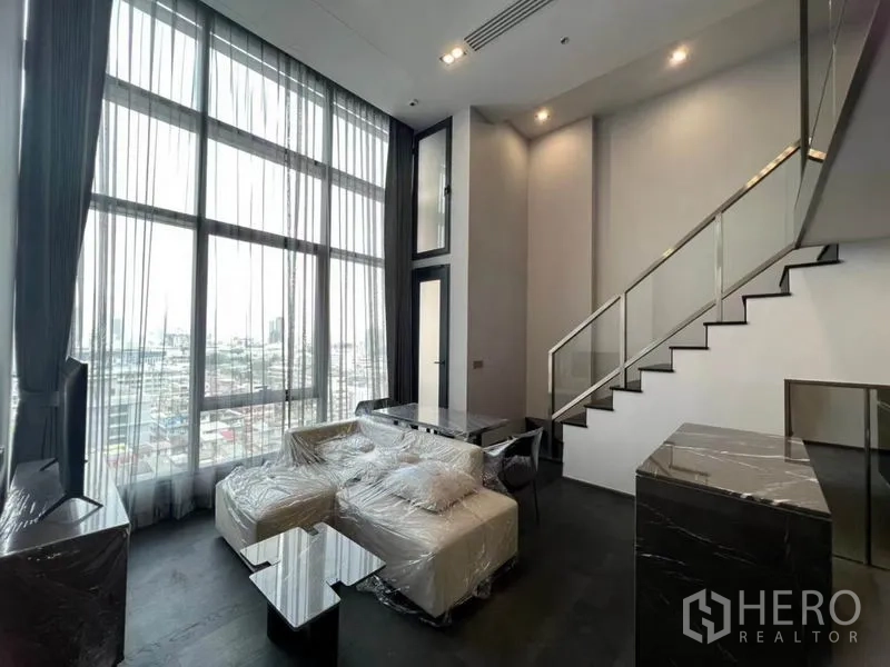 公寓 出租在Ratchathewi, Bangkok - Loft客厅，挑高中庭与落地窗，俯瞰城市景观，位于拉差贴威公寓。
