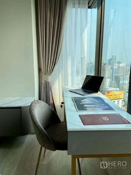 公寓 出租在Pathum Wan, Bangkok - 落地窗旁的紧凑书桌，配窗帘与城市景色。