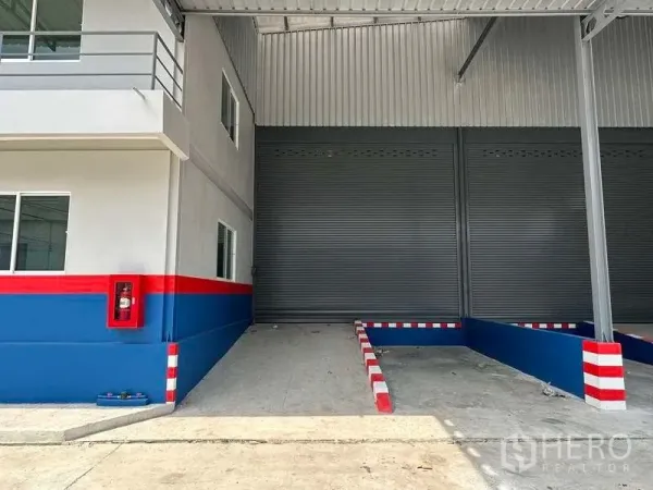 คลังสินค้า ให้เช่าในSamut Prakan - ภาพระยะใกล้ของจุดโหลดสินค้าที่มีประตูม้วน ทางลาด และตู้สายฉีดน้ำดับเพลิง