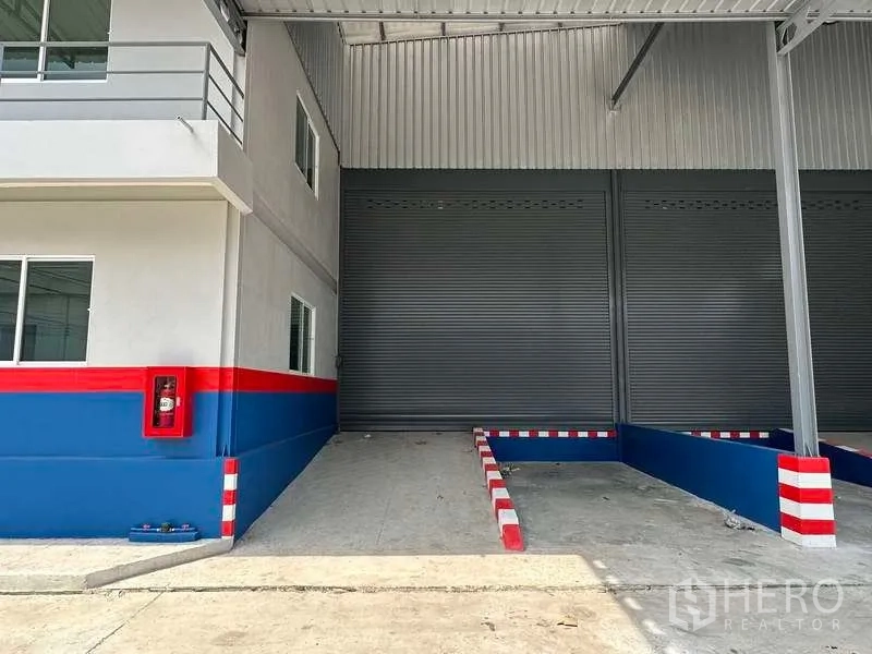 คลังสินค้า ให้เช่าในSamut Prakan - ภาพระยะใกล้ของจุดโหลดสินค้าที่มีประตูม้วน ทางลาด และตู้สายฉีดน้ำดับเพลิง