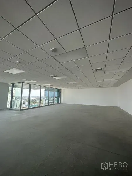 Office Space for rent in Bang Na, Bangkok - Unfurnished office corner with glass curtain wall, city views and recessed ceiling fixtures.