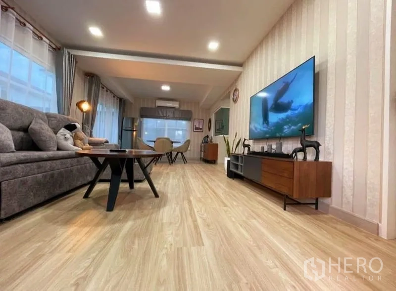 Detached House for rent or sale - Open-plan living and dining area with wood-look flooring, sofa and a large wall-mounted TV