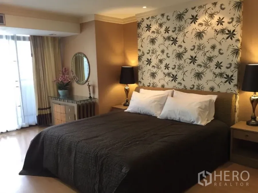 Condominium for rent in Watthana, Bangkok - Master bedroom with floral feature wall, dark bedspread, bedside lamps and balcony curtains in a Thonglor condo.
