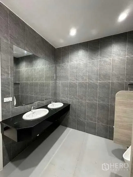 Warehouse for rent in Bang Phli, Samut Prakan - Modern restroom with double sinks, large mirror and gray tiled walls.