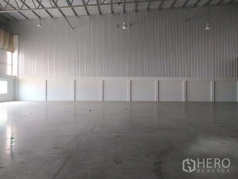 Warehouse for rent in Bang Sao Thong, Samut Prakan - Empty warehouse space with corrugated metal walls, high-bay lighting and a wide clear span ready for storage or production.