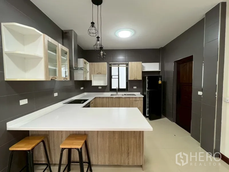 บ้าน ขายในPhra Khanong, Bangkok - ครัวพร้อมเคาน์เตอร์บาร์ ไฟห้อยตกแต่ง และตู้เย็นขนาดใหญ่