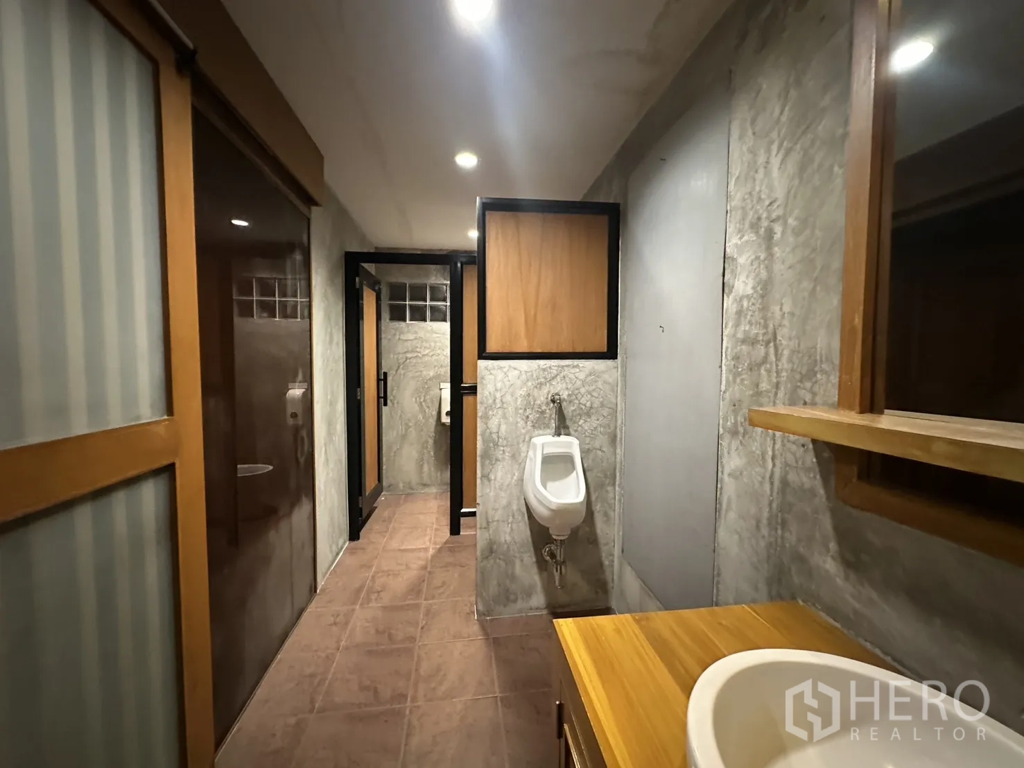Retail Space for rent in Watthana, Bangkok - Restroom corridor with urinal, cubicles, and wood‑accented partitions.