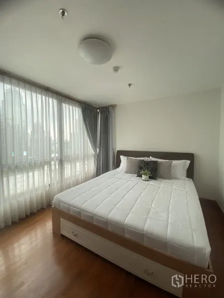 คอนโด ให้เช่าในPathum Wan, Bangkok - ห้องนอนมาสเตอร์มุมห้อง หน้าต่างสูงจรดเพดาน เตียงคิงไซส์ และวิวเมือง