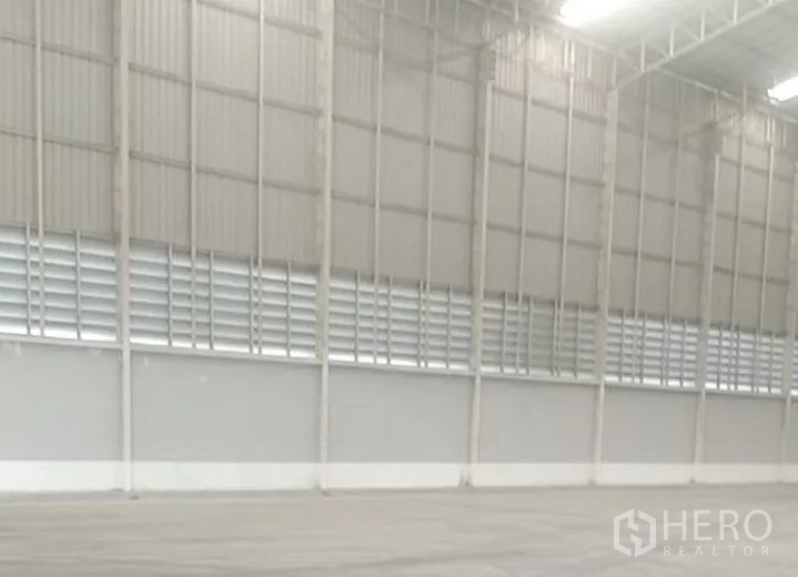 Warehouse for rent in Phra Nakhon Si Ayutthaya - Warehouse corner with three red trucks parked beneath the high roof.