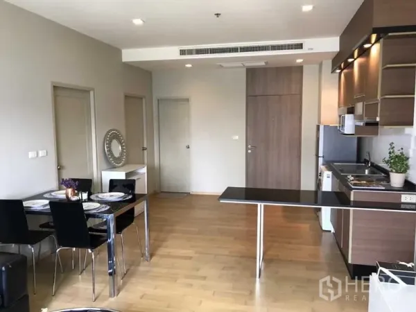 Condominium for rent in Watthana, Bangkok - Dining corner for four beside an extended breakfast bar and full kitchen on light wood flooring.