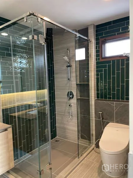 Detached House for rent in Bang Kapi, Bangkok - Second bathroom with glass shower and glossy green tile accent wall.