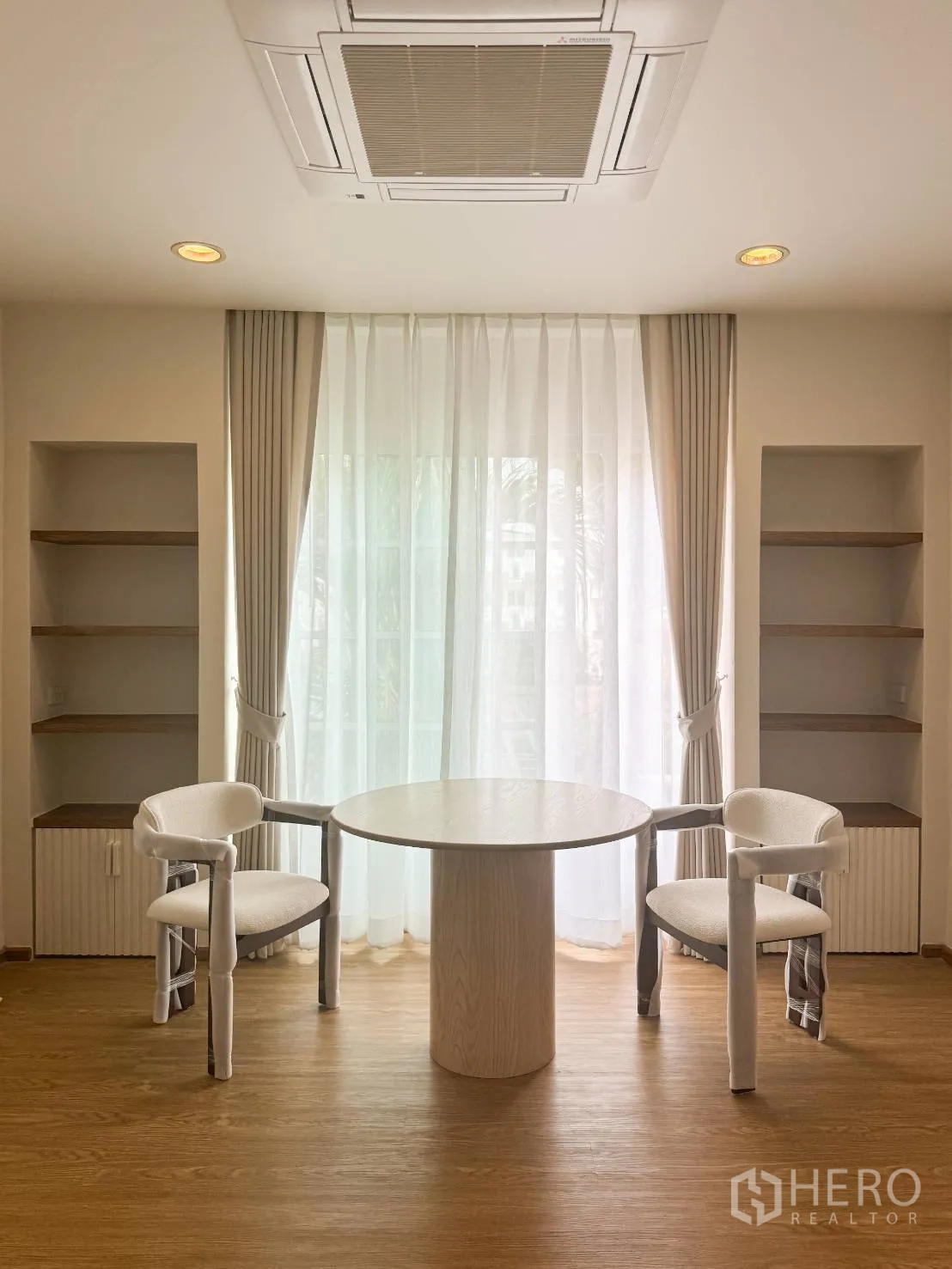 Shophouse for sale in Watthana, Bangkok - Bright seating area with round table, two chairs, built-in shelves and sheer curtains.