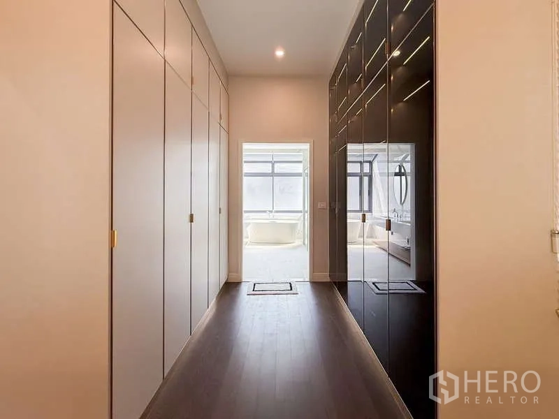 Detached House for rent or sale in Bang Kapi, Bangkok - Dressing hallway with built-in wardrobes leading to a naturally lit bathroom.