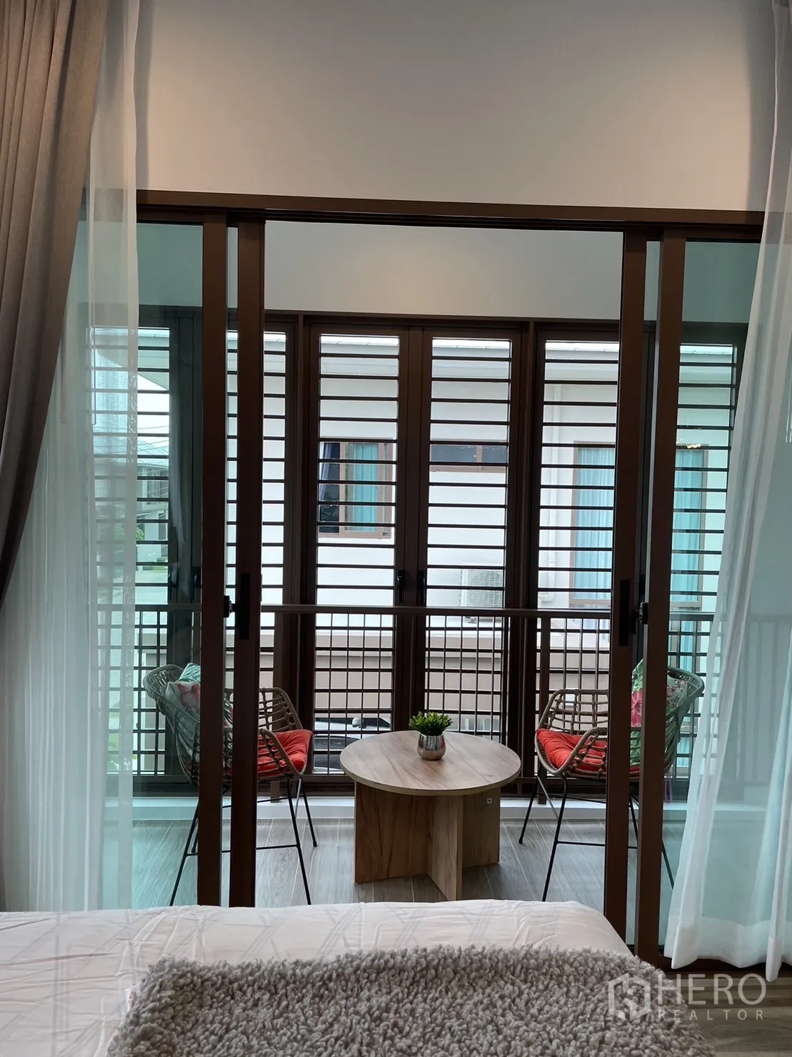 Detached House for rent in Bang Kapi, Bangkok - Cozy balcony with two chairs and a round table behind louvered screens.