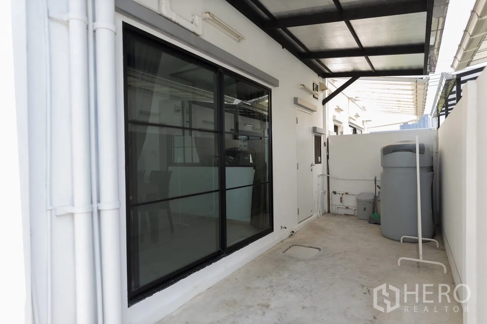 Townhouse for rent in Bang Phli, Samut Prakan - Covered utility area with water tank beside a sliding door and service door.