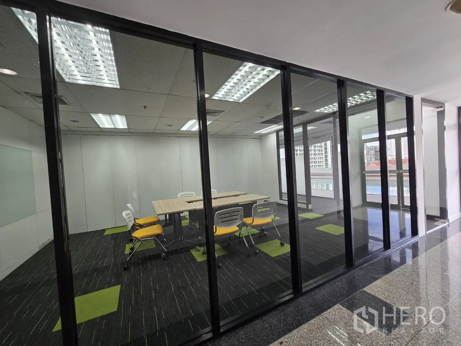 Office Space for rent in Watthana, Bangkok - Conference room with table and yellow chairs behind glass, facing large windows.