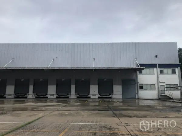 工厂 出租在Phra Nakhon Si Ayutthaya - 一排装卸月台与卷帘门，旁接办公楼的工厂立面。