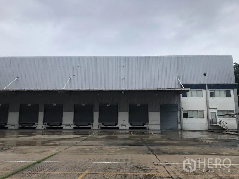 工厂 出租在Phra Nakhon Si Ayutthaya - 一排装卸月台与卷帘门，旁接办公楼的工厂立面。