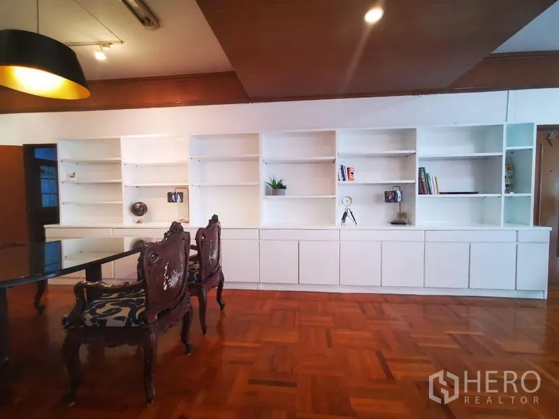 房间 出租在Khlong Toei, Bangkok - 餐区整面白色内置书柜，雕花椅与吊灯。