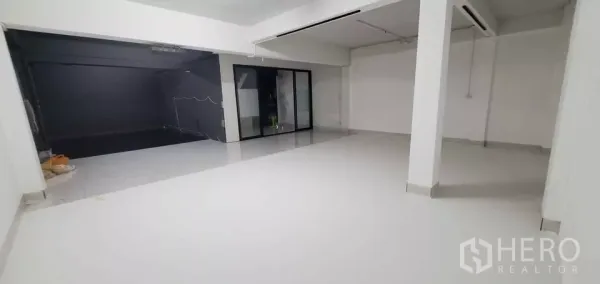 Office Space for rent in Suan Luang, Bangkok - Bright white open-plan floor with tiled surface, support columns and a glass sliding partition.