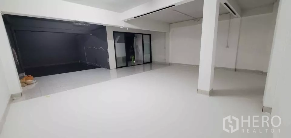 Office Space for rent in Suan Luang, Bangkok - Bright white open-plan floor with tiled surface, support columns and a glass sliding partition.
