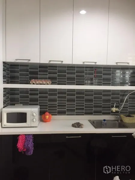 联排别墅 出租或出售在Wang Thonglang, Bangkok - 现代厨房，白色橱柜与黑色条纹瓷砖背景墙，配水槽和微波炉。