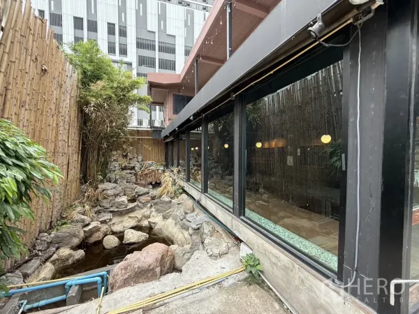 独立式住宅 出租在Watthana, Bangkok - 侧院竹篱与叠石水景，沿墙为整面玻璃窗