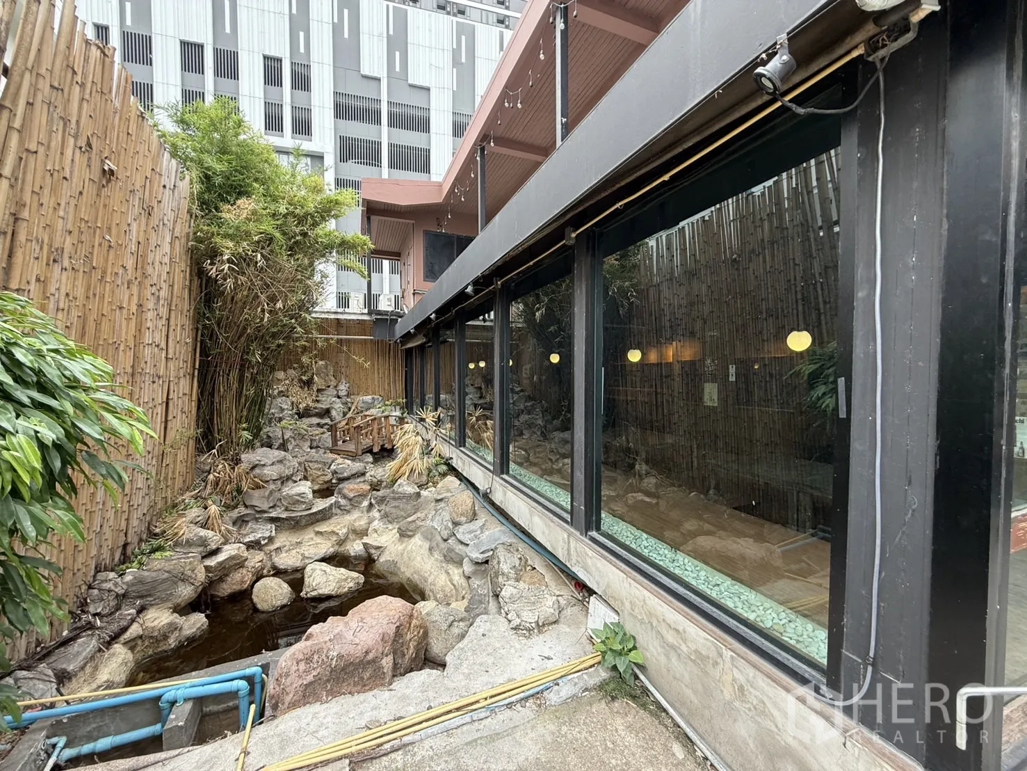 独立式住宅 出租在Watthana, Bangkok - 侧院竹篱与叠石水景，沿墙为整面玻璃窗