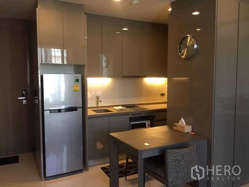 Condominium for rent in Bang Rak, Bangkok - Sleek grey kitchen with built-in hob, fridge, ample cabinetry and dining table.