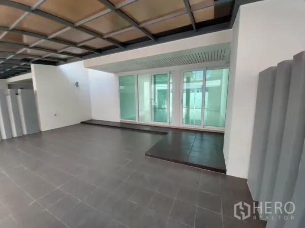 ทาวน์เฮาส์ ขายในWang Thonglang, Bangkok - ที่จอดรถมีหลังคาพร้อมพื้นกระเบื้องและประตูกระจกบานเลื่อนกว้างบริเวณทางเข้าทาวน์เฮ้าส์