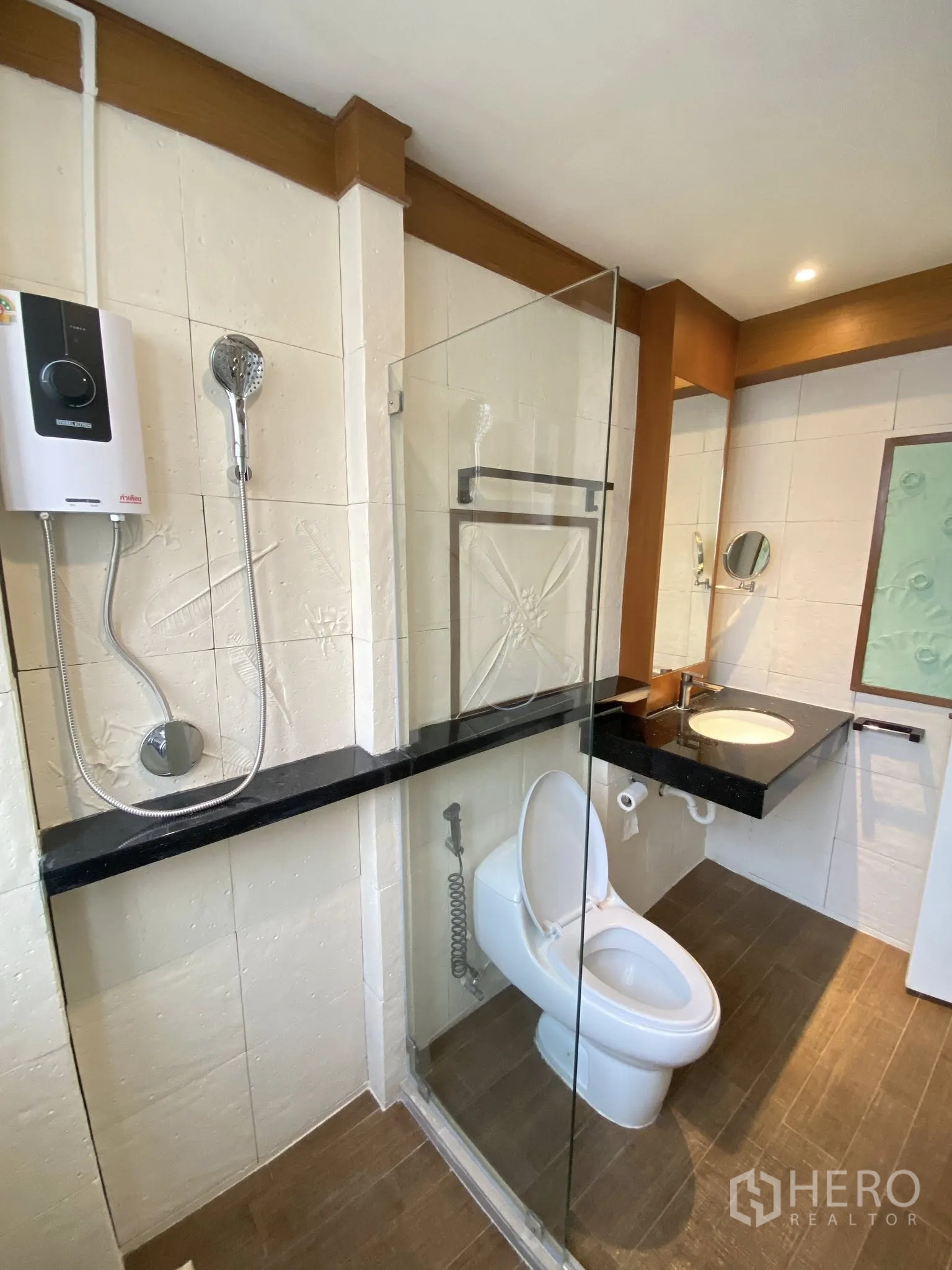 Home Office for rent in Pathum Wan, Bangkok - Bathroom with glass partition shower, water heater, and stone‑top basin.
