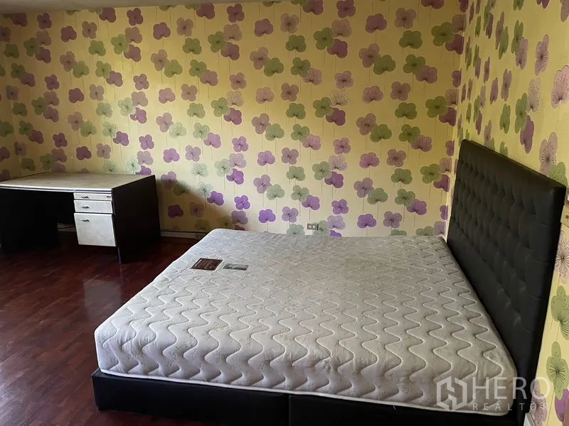 สำนักงานที่บ้าน ให้เช่าในWatthana, Bangkok - ห้องนอนวอลเปเปอร์ลายดอกไม้ พื้นไม้ เตียงบุนวม และโต๊ะทำงานมุมห้อง