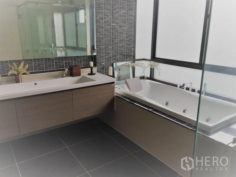 Detached House for rent or sale in Bang Kapi, Bangkok - Contemporary bathroom with double vanity, bathtub and a glass shower enclosure.