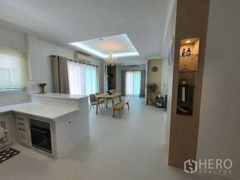 Detached House for rent in Saphan Sung, Bangkok - Open‑plan living and dining area featuring chandelier lighting, large curtains and a breakfast counter.