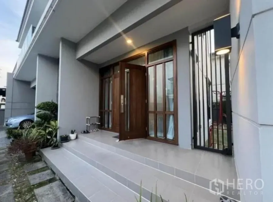 独立式住宅 出租 - 黄昏时的入户露台，铺设台阶与绿植，实木大门稳固。